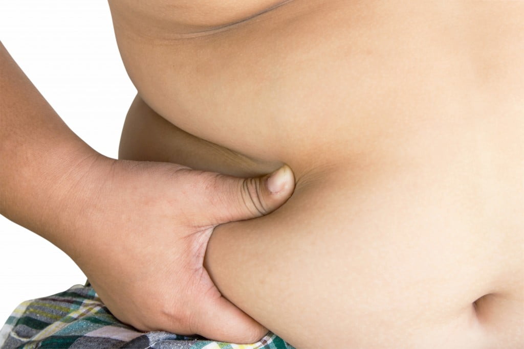 obesity: overweight person holds bulge over hip