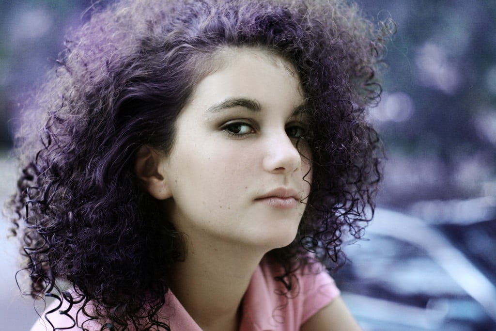 curly-haired woman wearing purple (colour of epilepsy) with purple streaked hair