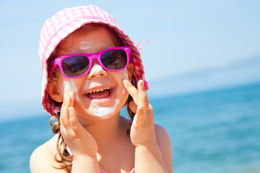 laughing girl at beach wearing big pink sunglasses