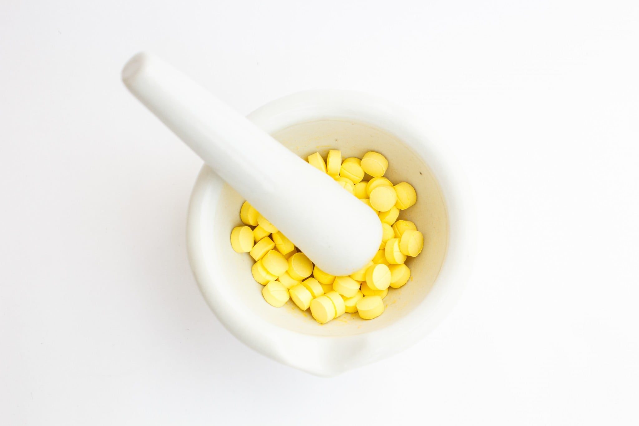 yellow pills in mortar with pestle for crushing medicines
