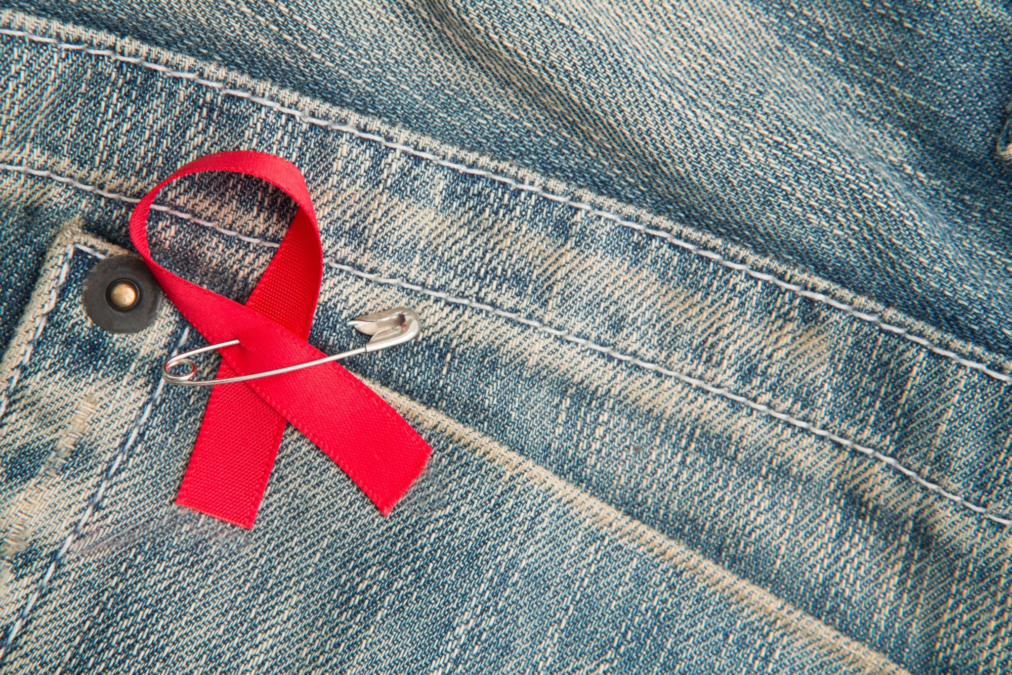 HIV red ribbon pinned to jeans pocket