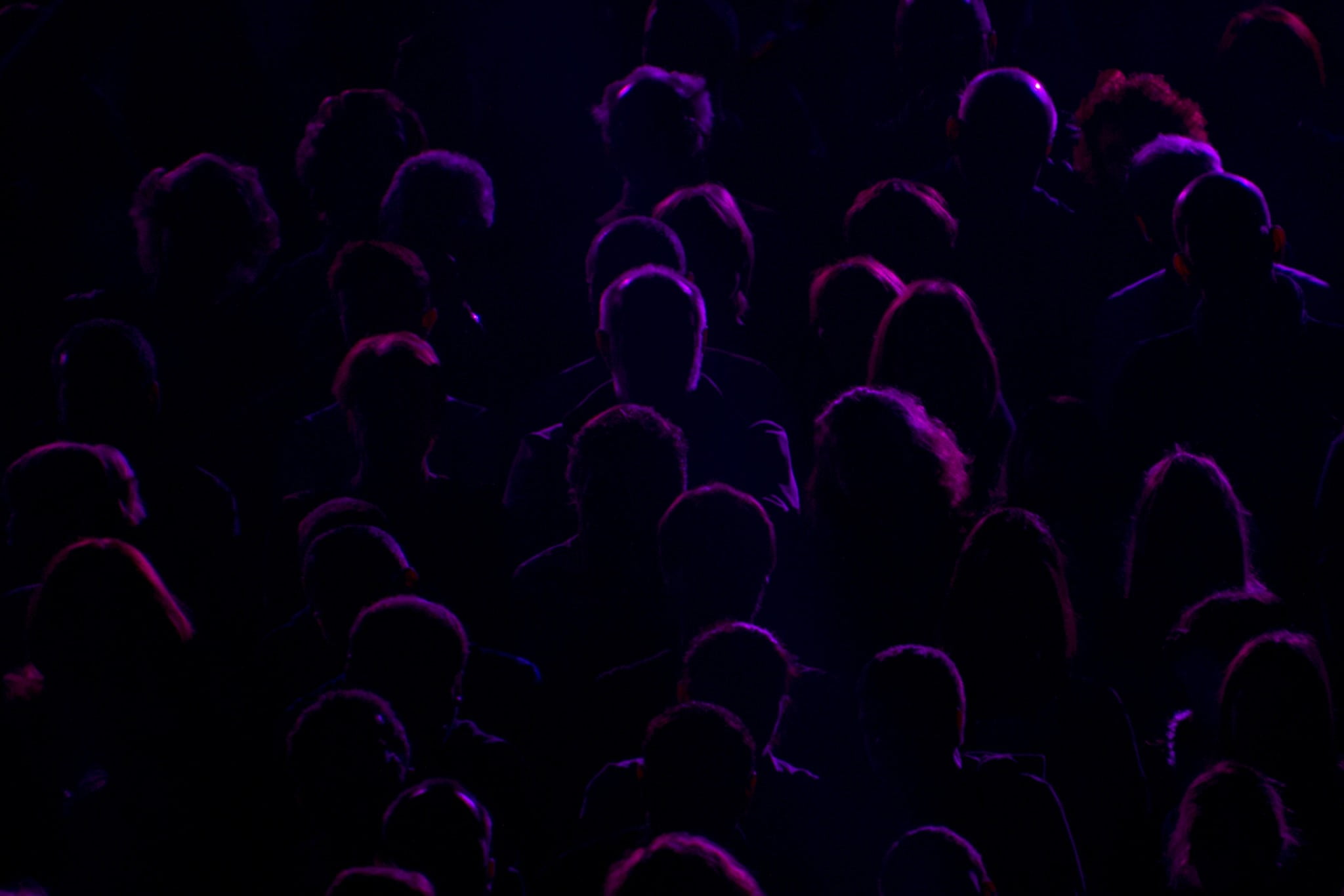 opioid concept: dim silhouettes lit with purple-red light