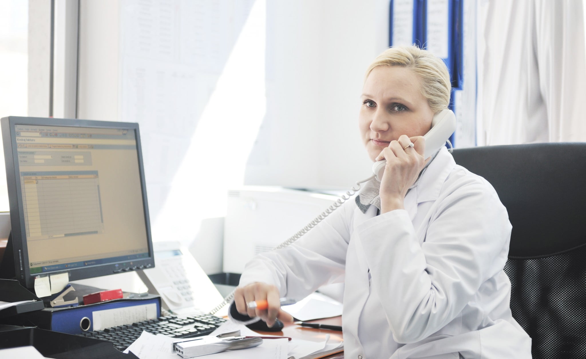 employee pharmacists: busy-looking pharmacist on hold on the phone