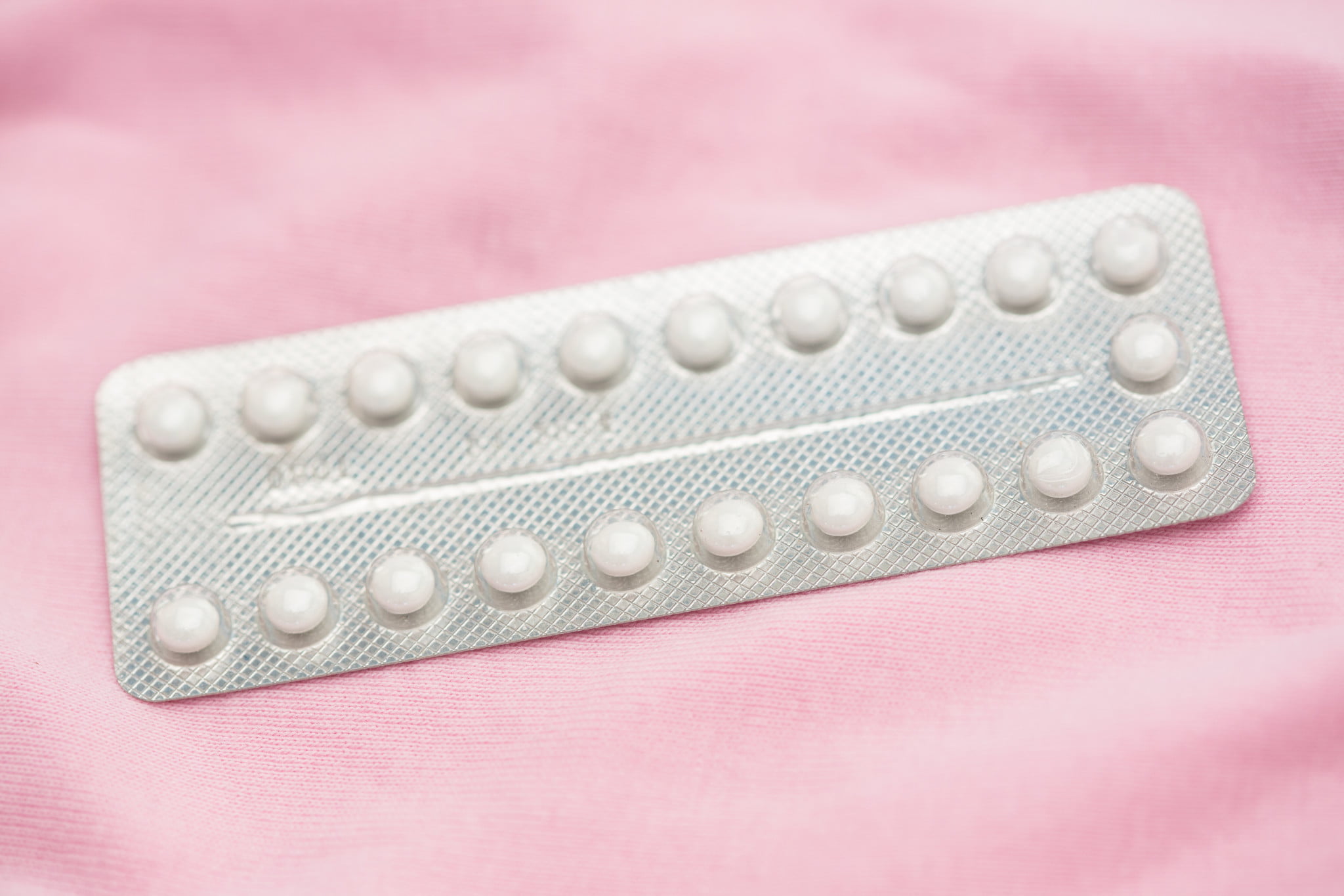 packet of contraceptive pills on pink background