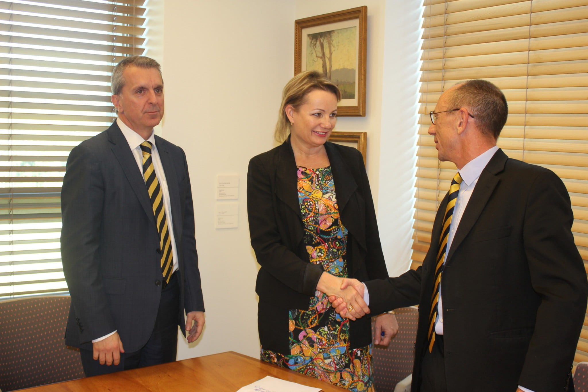 Pharmacy Guild's David Quilty shakes hands with Sussan Ley following signing of Sixth Community Pharmacy Agreement, George Tambassis in background