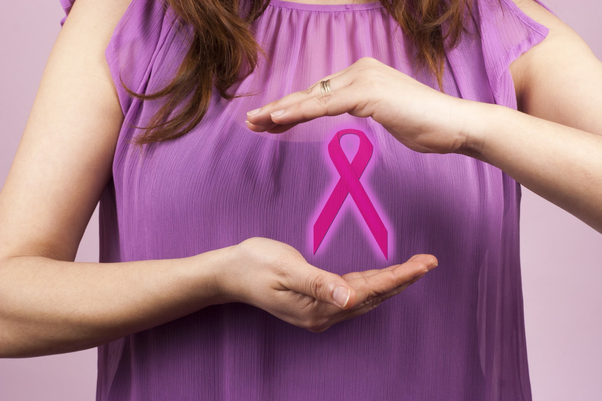 BreastScreen: woman in pink top holds pink ribbon