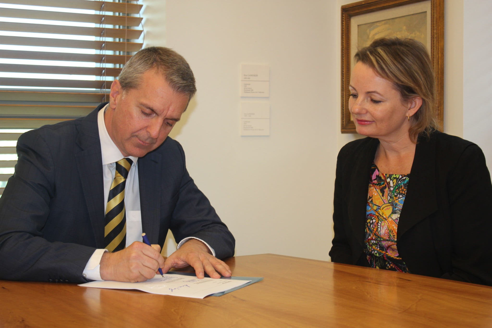 George Tambassis from the Pharmacy Guild signs the Sixth Community Pharmacy Agreement as Health Minister Sussan Ley looks on