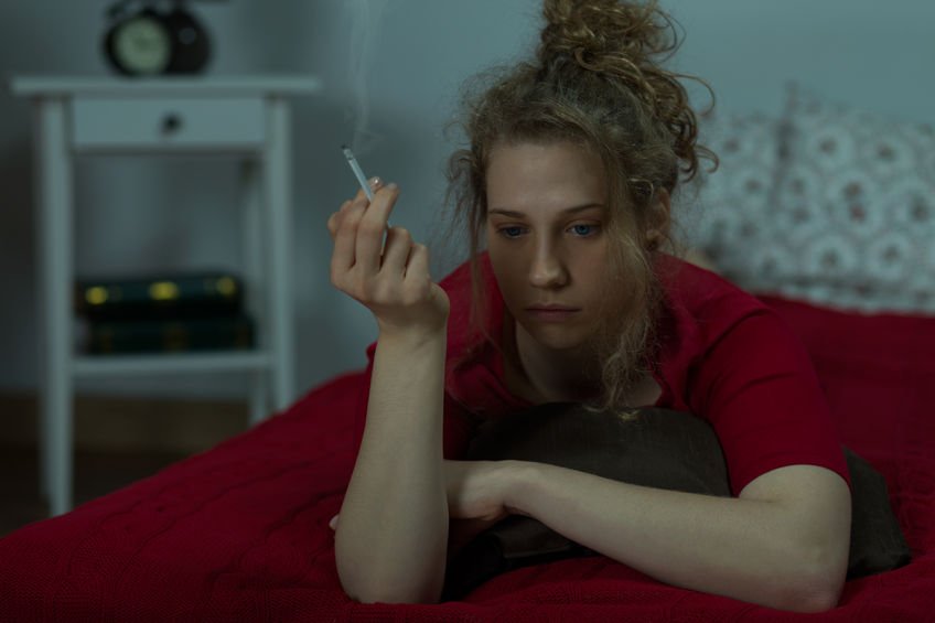 frazzled young woman smoking in dingy room