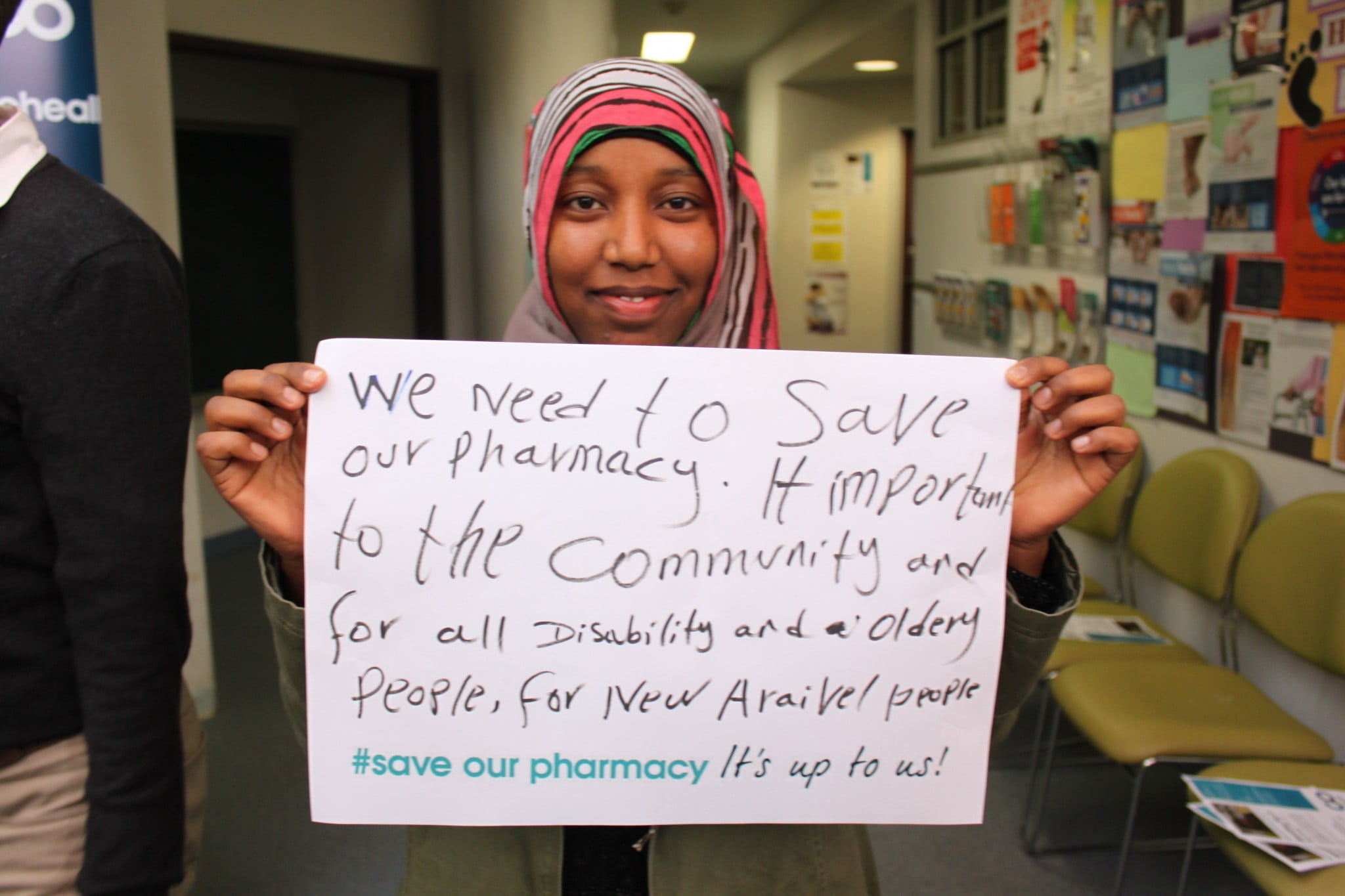 concerned cohealth Collingwood patient holds up sign in support of the pharmacy