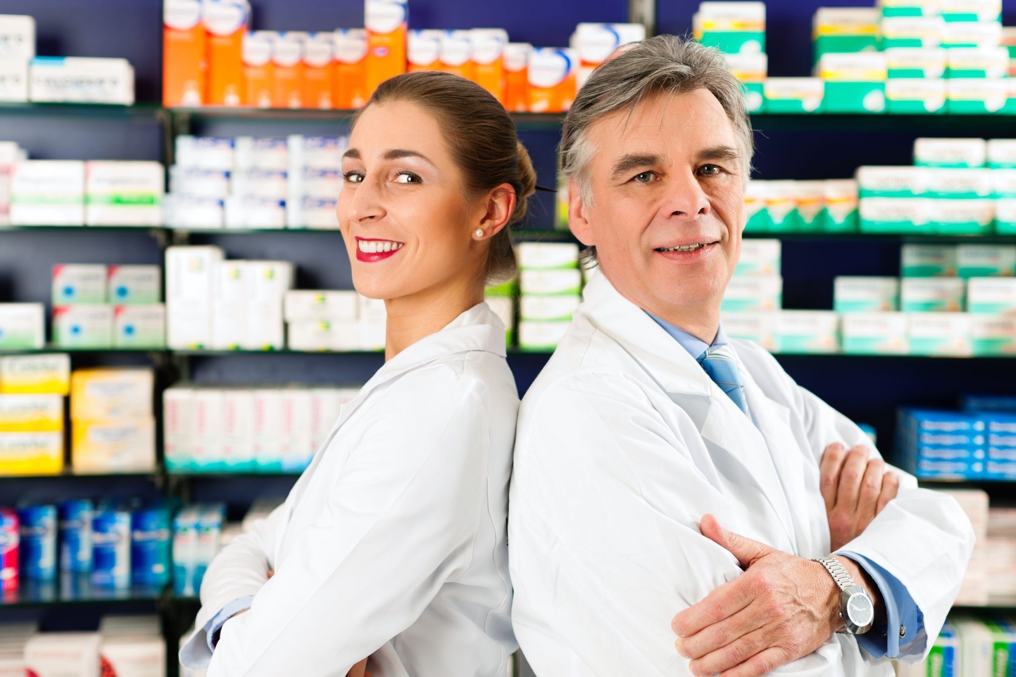 0016562 - two pharmacists standing in pharmacy or drugstore in front of shelves with pharmaceuticals