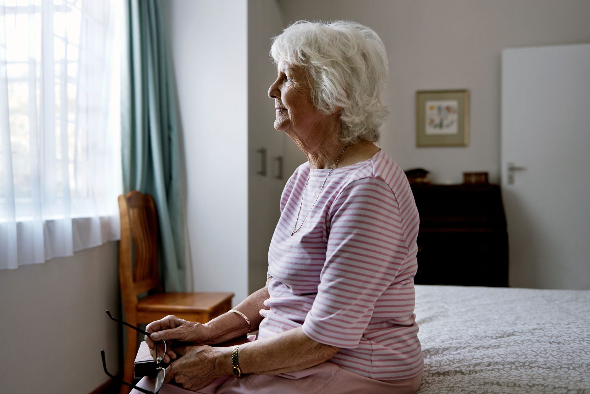 older woman sits on bed