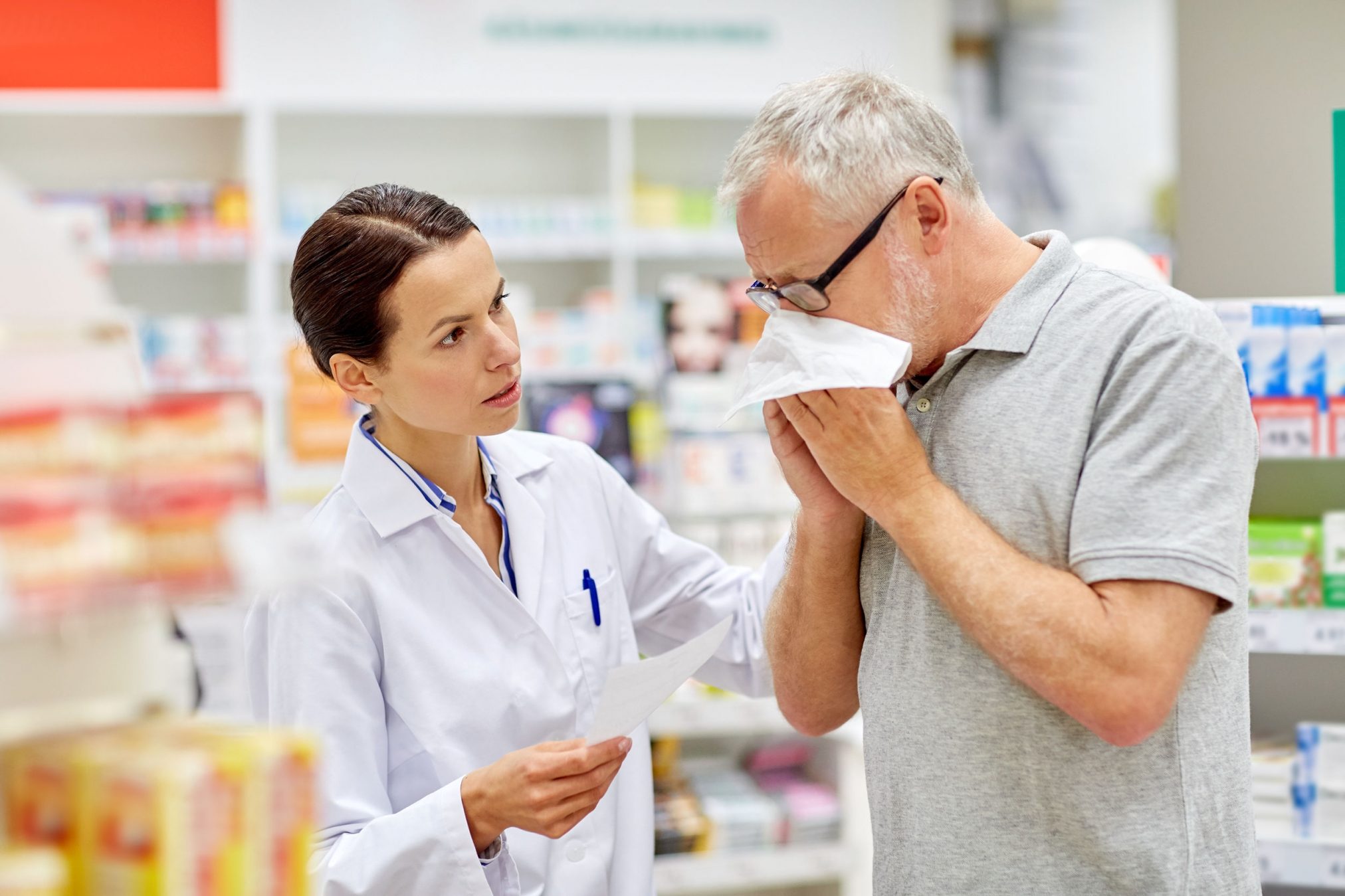 pharmacist with customer blowing his nose