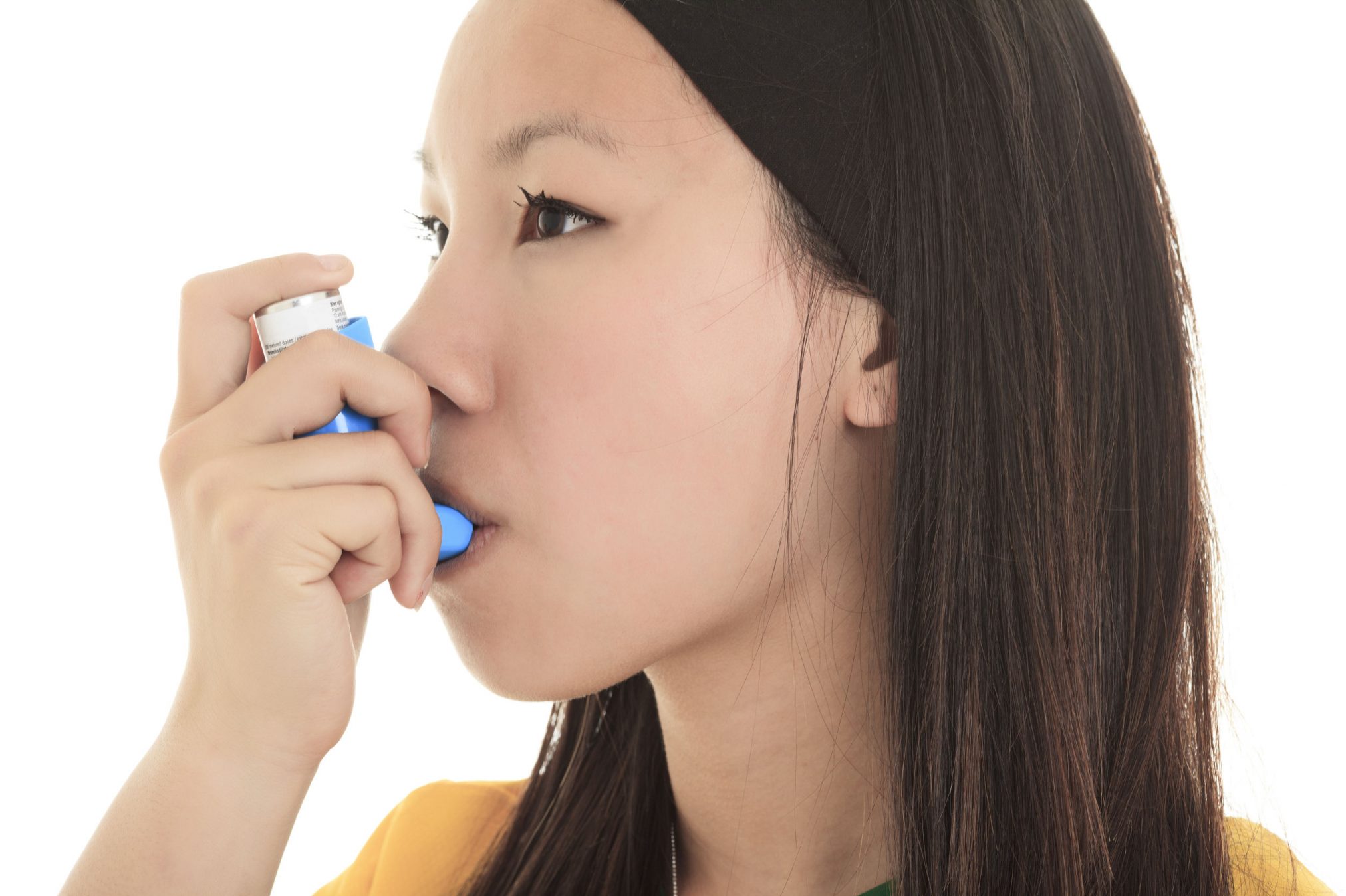 a close up image of a young woman using inhaler.