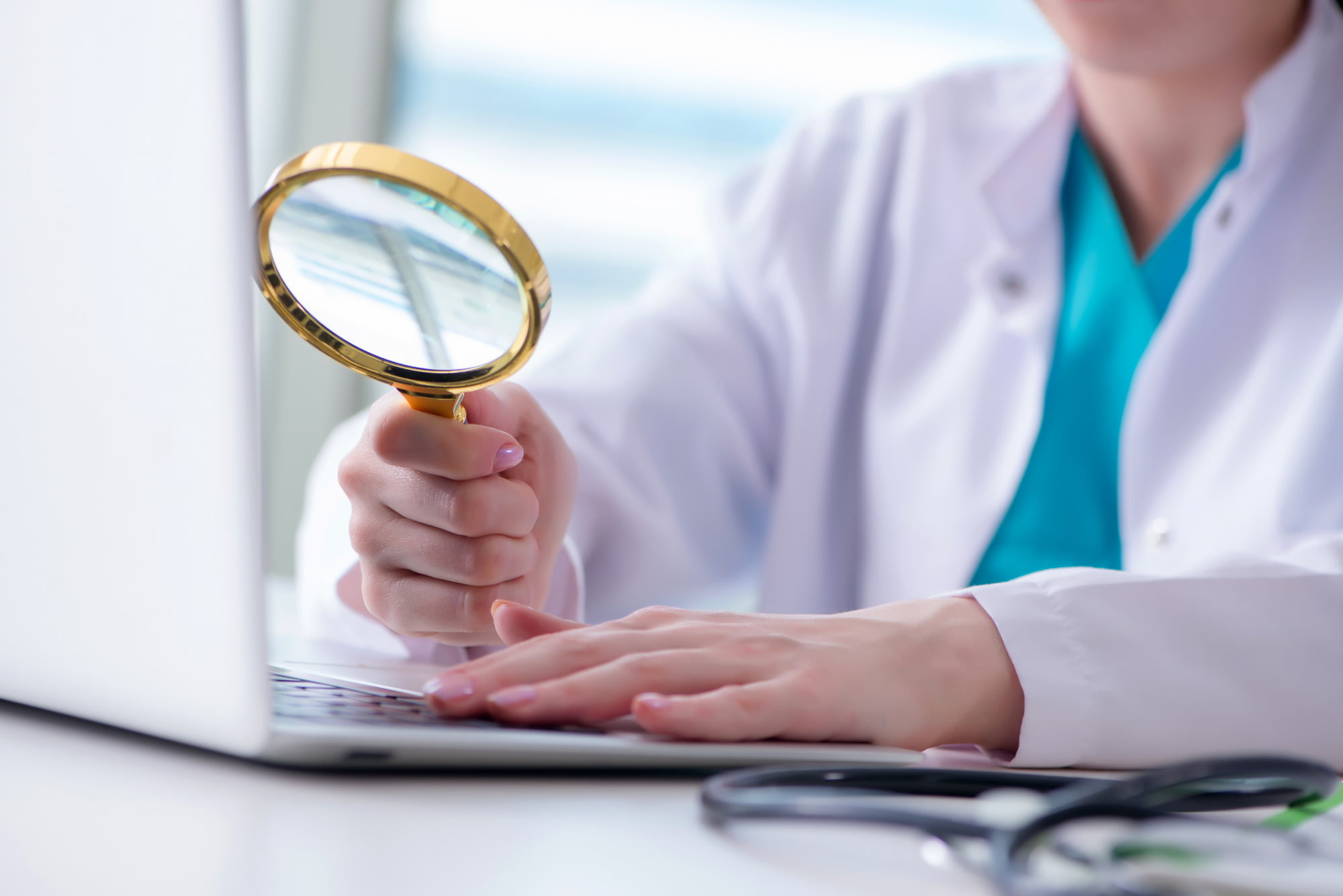 health professional at computer with magnifying glass