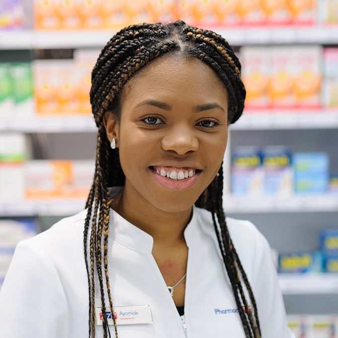 Smiling woman in pharmacy, wearing pharmacist white coat